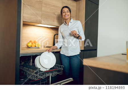 Dark-haired young woman in the kitchen near dishwasher 118194893