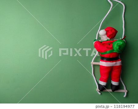 A statue of Santa Claus climbing the stairs on a green background with copy and text space. 118194977
