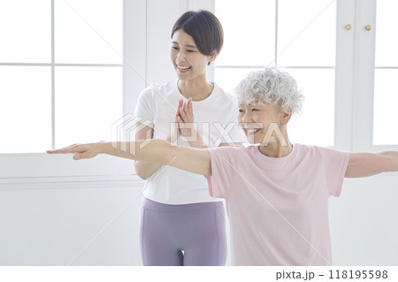 高齢者の女性にヨガを教えるインストラクター 118195598