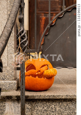 Exterior Beautiful atmospheric halloween carved pumpkins decorated on porch. Autumn leaves and fall flowers celebration holiday Thanksgiving October season 118196013