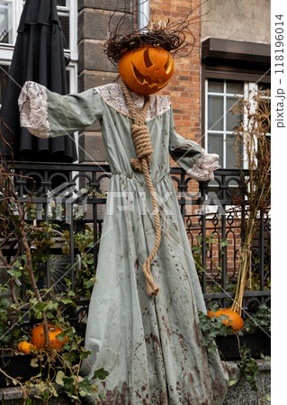 Halloween horror scarecrow decorated outdoor cafe or restaurant terrace in America or Europe with pumpkins traditional attributes of Halloween. Frontyard decoration 118196014