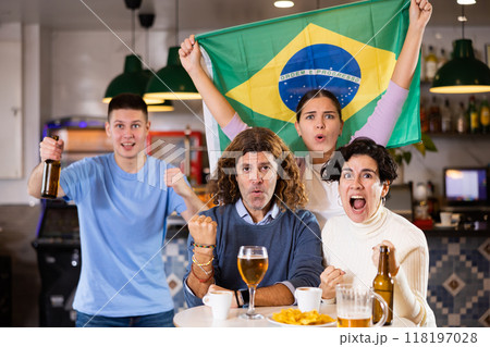 Happy friends of different ages drinking beer and celebrating the victory of the Brazilian team in night bar 118197028