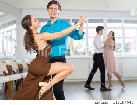 Girl and guy dancing slow ballroom dance during group class in choreography studio Girl and guy dancing slow ballroom dance during group class in choreography studio 118197040