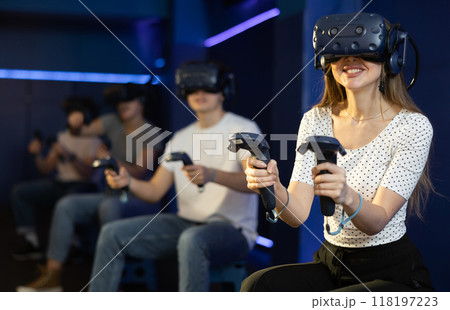 Young woman in virtual glasses plays virtual reality games with friends in special room Young woman in virtual glasses plays virtual reality games with friends in special room 118197223