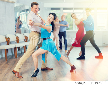 Portrait of adult pairs of different ages enjoying tango in modern dance hall together 118197300