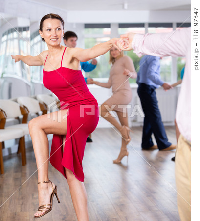 Enthusiastic woman learning dynamic dances with partner at choreography class Enthusiastic woman learning dynamic dances with partner at choreography class 118197347