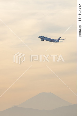 夕焼けの中を離陸する飛行機 118198342