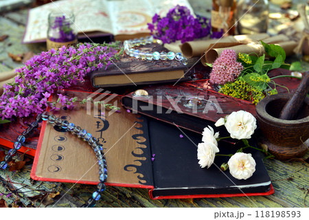 Mystic still life with magic book of spells, flowers and witchy ritual objects on old table. Occult, esoteric, wicca and divination concept. No foreign language, all symbols are fictional 118198593