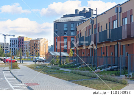 Construction of modern apartment blocks and townhouses in residential complex. Buildings and machinery on construction platform. Comfortable housing of new type.  118198958
