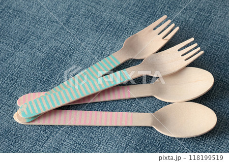Wooden colorful spoons and forks on mat under plate. Disposable eco-friendly tableware. Food and snacking. Background for design.  118199519