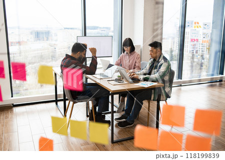 Architects brainstorming in modern office with sticky notes on glass 118199839