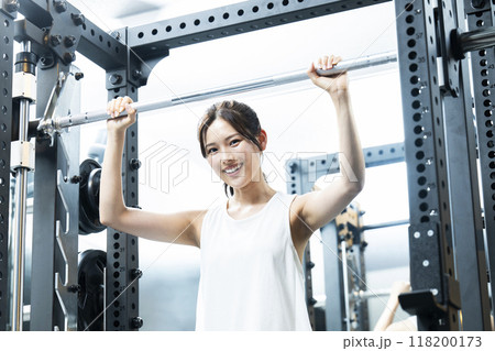 スポーツジムでトレーニングする若い女性　カメラ目線　笑顔 118200173