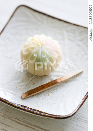 A piece of delicious Japanese confectionary on white ceramic plate on white wooden table. Selective focus. A piece of delicious Japanese confectionary on white ceramic plate on white wooden table. Selective focus. 118203003