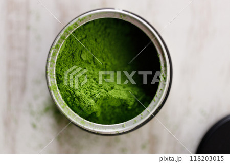 Closeup of fresh matcha powder on white wooden background. Selective focus. Closeup of fresh matcha powder on white wooden background. Selective focus. 118203015