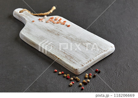 white wooden cutting board with scattered peppercorns and coarse pink salt on dark stone table white wooden cutting board with scattered peppercorns and coarse pink salt on dark stone table 118206669