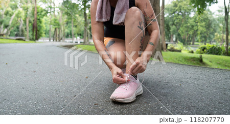 Close up of elderly woman tying shoelaces in park Close up of elderly woman tying shoelaces in park 118207770