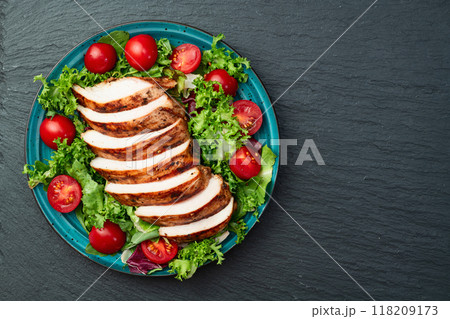 Grilled chicken breast ( fillet ) with lattuce salad and cherry tomatoes . Top view Grilled chicken breast ( fillet ) with lattuce salad and cherry tomatoes . Top view 118209173