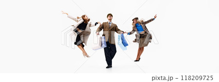 Banner. Leaping mid-air, group creates moment of shopping joy, with bags in hands against white studio background. 118209725
