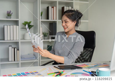 Graphic designer reviewing color drafts in modern office Graphic designer reviewing color drafts in modern office 118209815