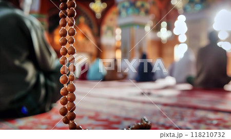 Prayer beads made of wood in the foreground with a blurred background of worshippers praying in a mosque 118210732