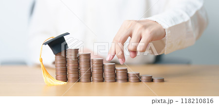 Money saving for Education, Scholarship, Student loan and debt and study future plan concept. Coins stack growing up with graduation hat on table 118210816