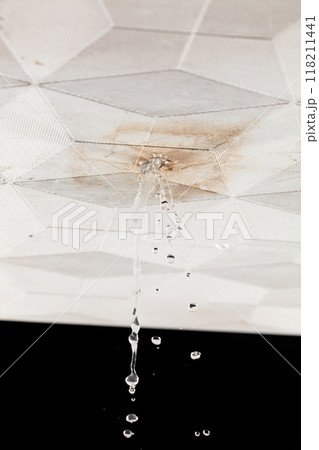 Ceiling Water leak from rain or broken pipe. House Water leaking on ceiling tile board and create dirty stain of flowing water, black background isolated Ceiling Water leak from rain or broken pipe. House Water leaking on ceiling tile board and create dirty stain of flowing water, black background isolated 118211441