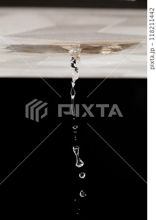 Ceiling Water leak from rain or broken pipe. House Water leaking on ceiling tile board and create dirty stain of flowing water, black background isolated 118211442