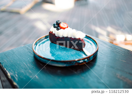 Piece of delicious homemade chocolate cake with fresh berry on a beautiful plate at city cafe, desert with chocolate Piece of delicious homemade chocolate cake with fresh berry on a beautiful plate at city cafe, desert with chocolate 118212530