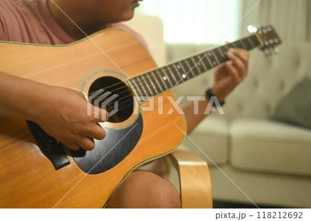 Cropped image of man playing an acoustic guitar in a cozy living room Cropped image of man playing an acoustic guitar in a cozy living room 118212692
