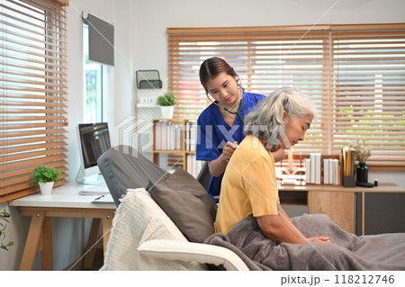 Healthcare professional in blue scrubs using a stethoscope to check breathing of an elderly female patient Healthcare professional in blue scrubs using a stethoscope to check breathing of an elderly female patient 118212746