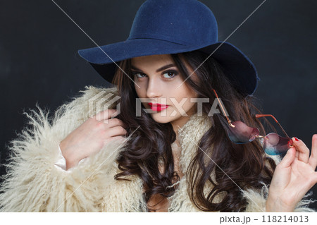 Portrait of woman with red lips make-up and long wavy hair wearing blue hat Portrait of woman with red lips make-up and long wavy hair wearing blue hat 118214013