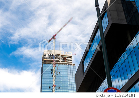Skyscraper under construction with a crane on a blue sky background. 118214191