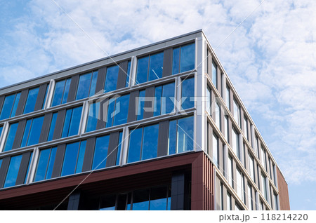 Low-angle view of a modern office building with glass windows against a blue sky Low-angle view of a modern office building with glass windows against a blue sky 118214220