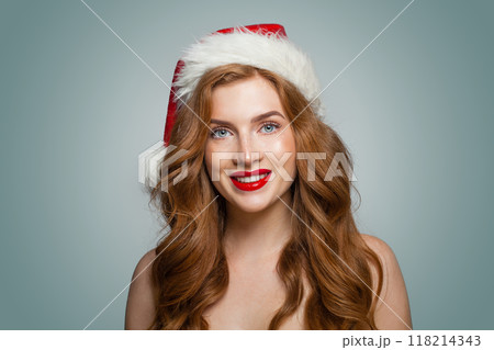 Gorgeous Christmas woman in Santa hat with make-up and cute positive smile looking at camera Gorgeous Christmas woman in Santa hat with make-up and cute positive smile looking at camera 118214343