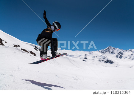 young woman snowboarder jumping from a springboard in the snowy mountains young woman snowboarder jumping from a springboard in the snowy mountains 118215364