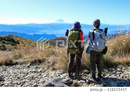 山梨県山梨市にある乾徳山の月見岩付近で富士山を眺める女性登山者二人の後ろ姿 118215437