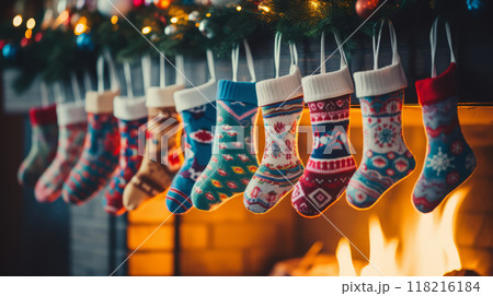 Multi-colored Christmas stockings hang above the fireplace with fire. Waiting for the holiday and gifts. Cozy atmosphere 118216184
