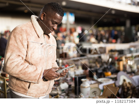 Man in a jacket chooses antiques at a flea market 118217384