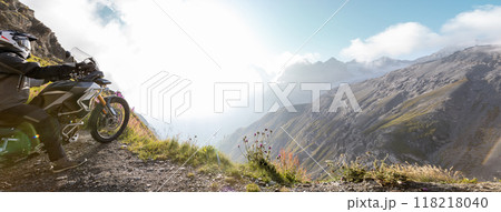 Motorbiker posing on motorbike in Italian Alps during sunrise, dramatic sky. Travel and freedom, outdoor activities 118218040