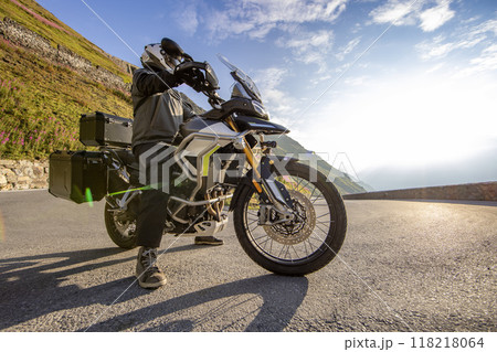Motorbiker riding in Italian Alps during sunrise, dramatic sky. Travel and freedom, outdoor activities Motorbiker riding in Italian Alps during sunrise, dramatic sky. Travel and freedom, outdoor activities 118218064