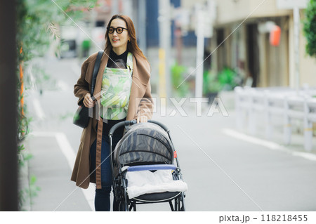 赤ちゃんを抱いて歩く母親 赤ちゃんを抱いて歩く母親 118218455