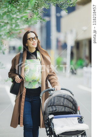 赤ちゃんを抱いて歩く母親　 118218457