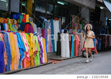 A woman walks down a street with a colorful display of fabrics A woman walks down a street with a colorful display of fabrics 118219589