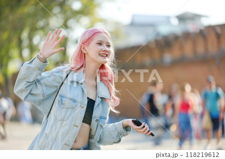 A woman with pink hair is waving to people on a street 118219612