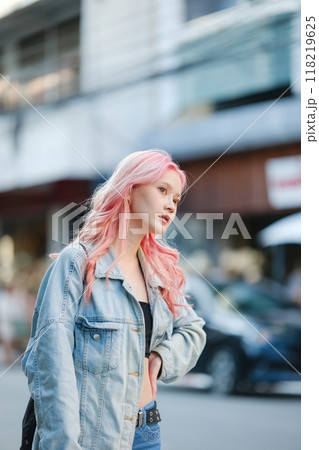 A woman with pink hair stands on a city street 118219625
