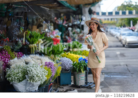 A woman is walking down a street with a bouquet of flowers in her hand 118219628