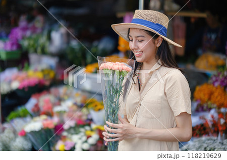 A woman is holding a bouquet of flowers and wearing a straw hat 118219629