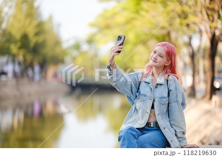 A woman with pink hair is taking a selfie with her cell phone 118219630