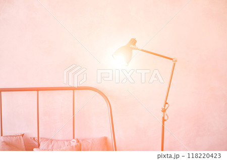 Minimalist bedroom with soft lighting and stylish bedside lamp against warm Minimalist bedroom with soft lighting and stylish bedside lamp against warm 118220423