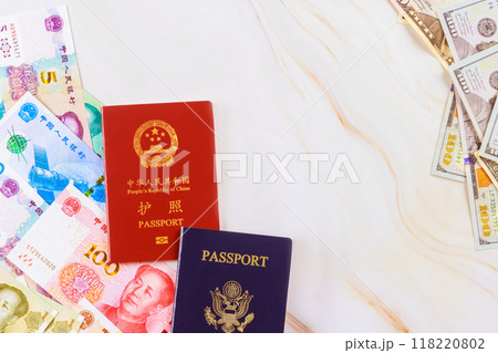 Passports from China, United States with Chinese cash yuan, US dollar banknotes of various denominations symbolizes confrontation between two nations economies 118220802